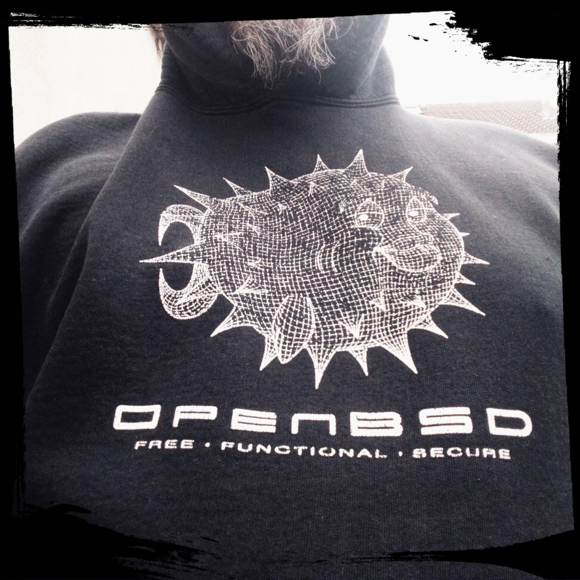 photo en gros plan du logo openbsd en noir et blanc avec le poisson.
on vois le bas du visage avec des poils de barbe blanc et gris