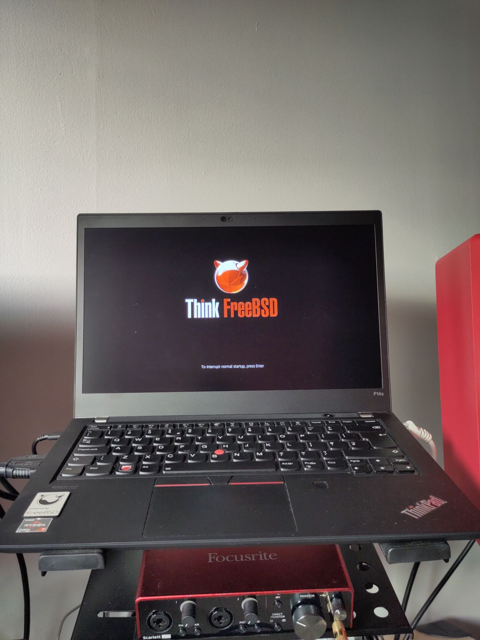 A photo of my ThinkPad displaying my new custom boot logo which has the FreeBSD orb logo at the top and the text in white saying "Think" with a red circle replacing the dot above the I. Then the text continues but in red "FreeBSD"